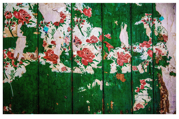 LAYERS OF RETRO FLORAL WALLPAPERS UNTIDILY RIPPED FROM A WOODEN PARTITION.